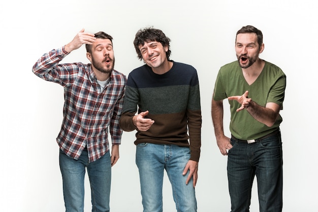 Foto gratuita los tres jóvenes sonrientes, de pie en blanco con diferentes emociones.