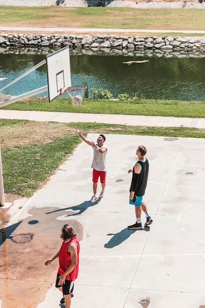 Tres jugadores mirando baloncesto cayendo de la red