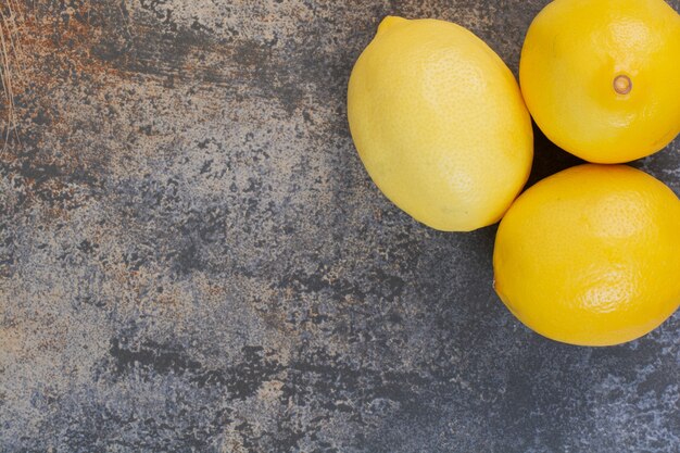 Tres limones enteros frescos en el espacio de mármol.