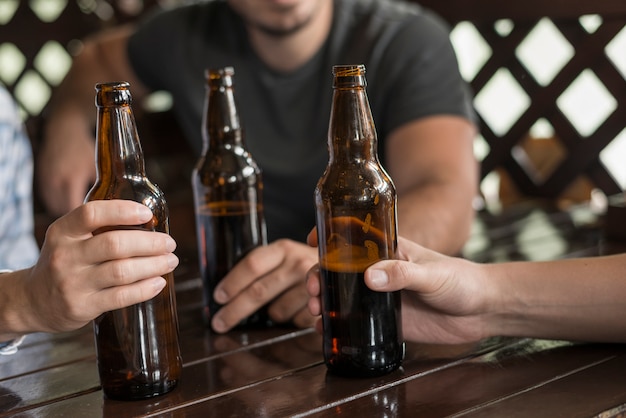 Tres manos con botellas de cerveza en la mesa