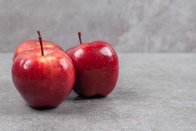 Tres manzanas rojas sobre la superficie de mármol