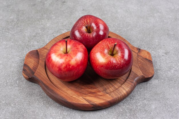 Tres manzanas rojas sobre tabla de madera