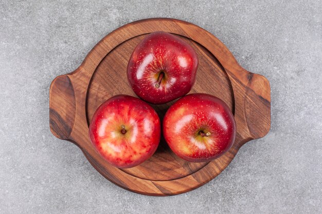 Tres manzanas rojas sobre tabla de madera