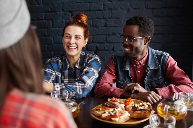 Tres mejores amigos disfrutando de una agradable conversación durante el almuerzo en el interior de la cafetería moderna