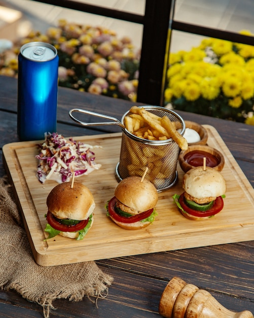 Tres mini hamburguesas de pollo servidas con papas fritas, mayonesa de col y salsa de tomate