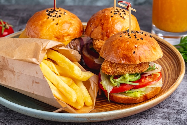 Tres mini hamburguesas servidas con papas fritas en una caja de papel