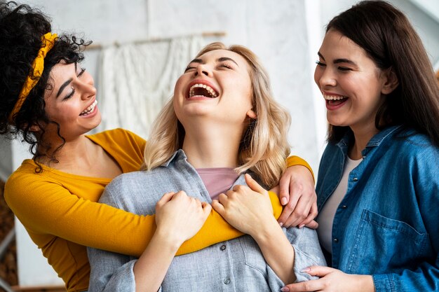 Tres mujeres abrazados riendo juntos