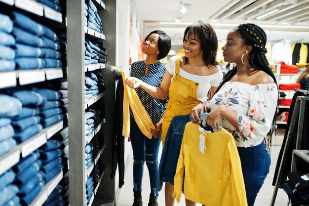 Tres mujeres africanas eligiendo ropa en la tienda Día de compras Están comprando jeans
