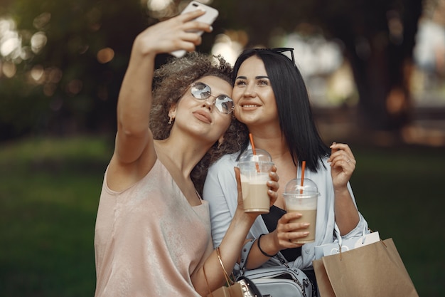 Tres mujeres elegantes con bolsas de compras en una ciudad