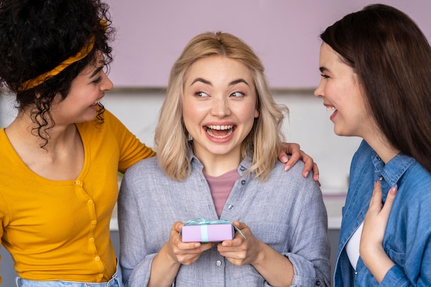 Tres mujeres felices sonrientes dándose regalos