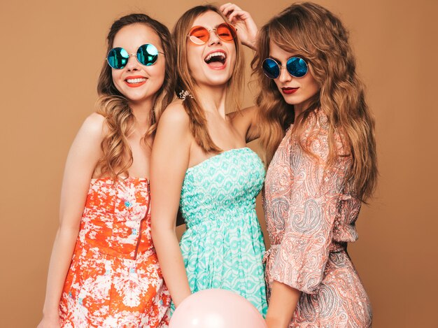 Tres mujeres hermosas sonrientes en vestidos de verano. Chicas posando Modelos con globos de colores. Divirtiéndose, listo para la celebración de cumpleaños o fiesta