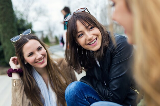 Tres mujeres jóvenes hablando y riendo en la calle.