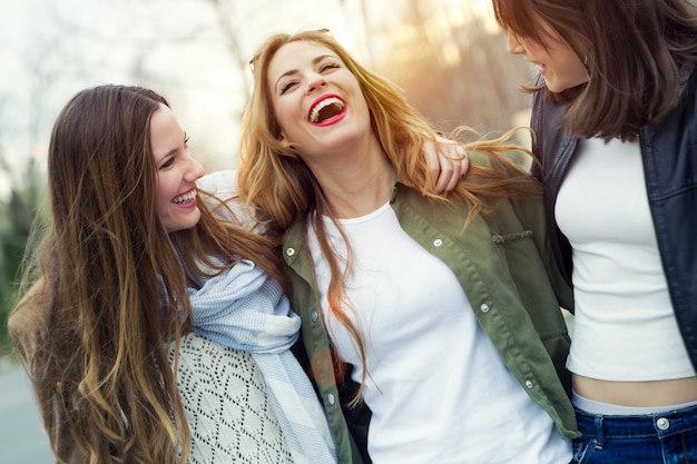 Tres mujeres jóvenes hablando y riendo en la calle.