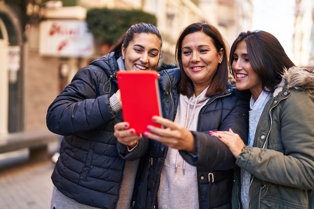 Tres mujeres madre e hijas que tienen videollamadas en la calle