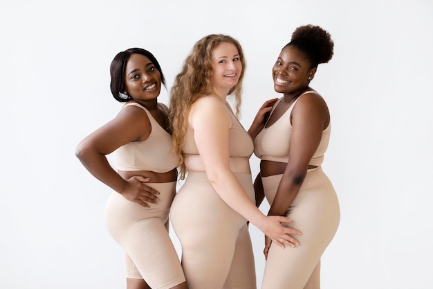 Tres mujeres sonrientes posando juntas en modeladores corporales