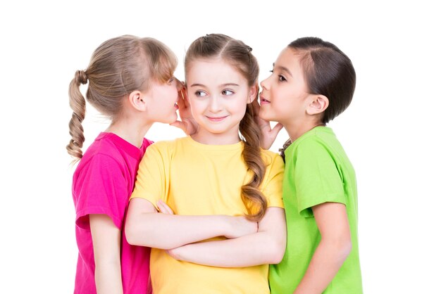 Tres niña sonriente linda en chismes de camisetas coloridas - aislado en blanco.