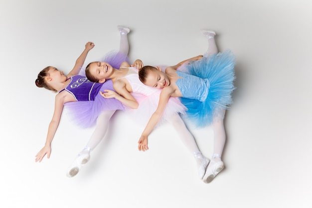 Foto gratuita tres niñas de ballet en tutú acostado y posando juntos
