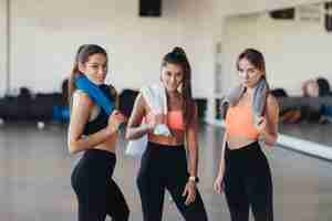 Foto gratuita tres niñas positivas sonrientes felices después de entrenar en el gimnasio. están mirando a la cámara. horizontal.