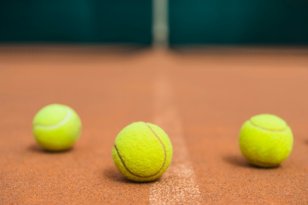 Tres pelotas de tenis verdes en la cancha de tenis.