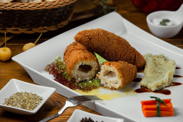 tres piezas de pollo kiev con puré servido en plato blanco