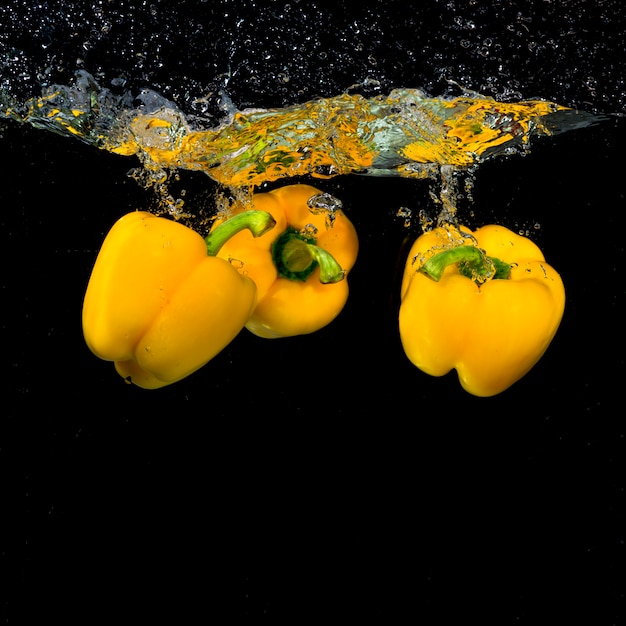 Tres pimientos amarillos flotando bajo el agua