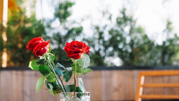 Tres rosas rojas en el jarrón de vidrio