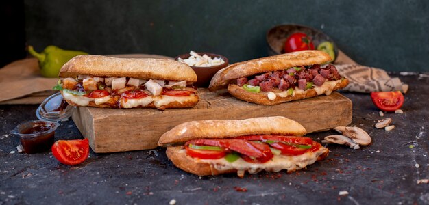 Tres sándwiches de baguette diferentes con alimentos mixtos en una mesa de piedra