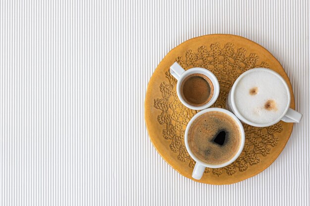 Tres tazas de café sobre un fondo de textura blanca endecha plana