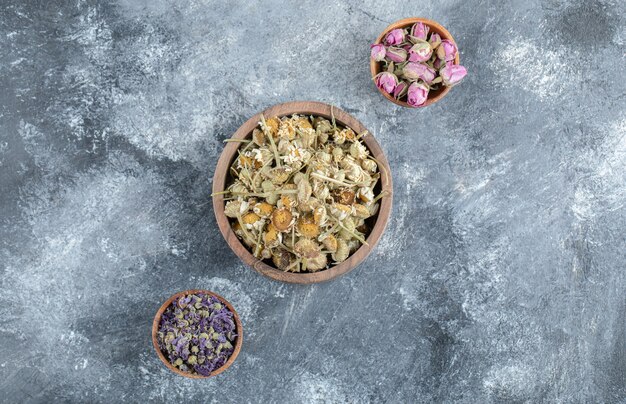 Tres tazones de té de flores secas en la mesa de mármol.