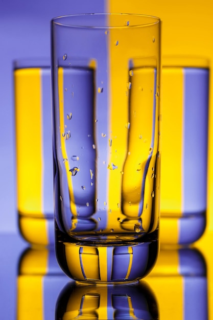 Foto gratuita tres vasos con agua sobre morado y amarillo.