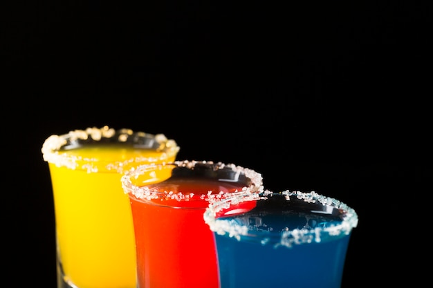 Foto gratuita tres vasos de chupito con cóctel de color y borde de sal