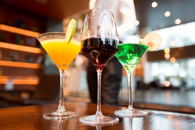 Tres vasos de diferentes bebidas alcohólicas en la barra