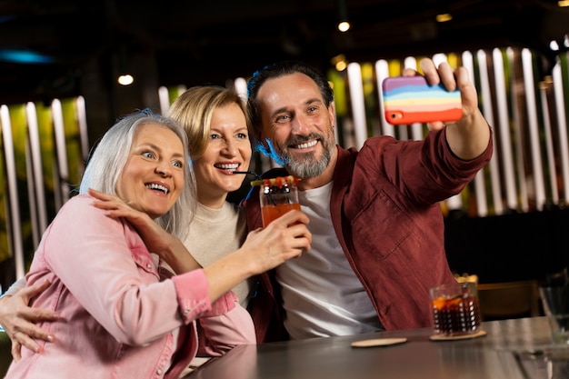 Tres viejos amigos haciéndose un selfie en un restaurante