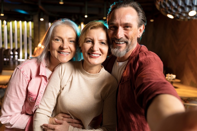 Tres viejos amigos haciéndose un selfie en un restaurante