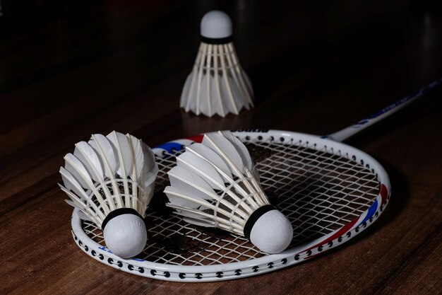 Tres volantes blancos y una raqueta de bádminton.