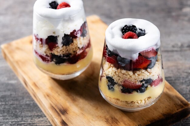 Trifle postre con bayas y crema sobre mesa de madera