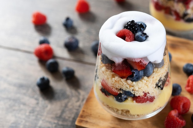 Trifle postre con bayas y crema sobre mesa de madera