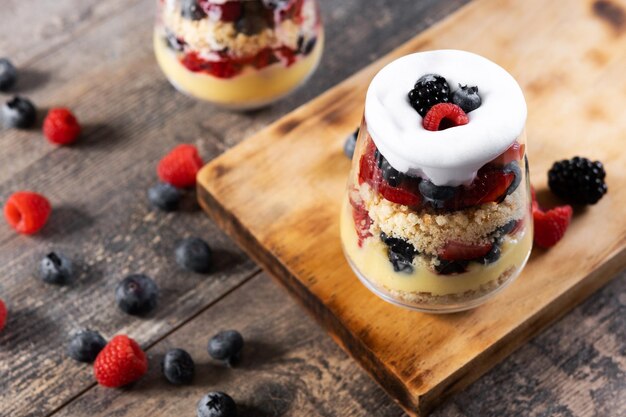 Trifle postre con bayas y crema sobre mesa de maderapostre típico inglés