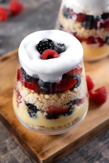 Trifle postre con bayas y crema sobre mesa de maderapostre típico inglés