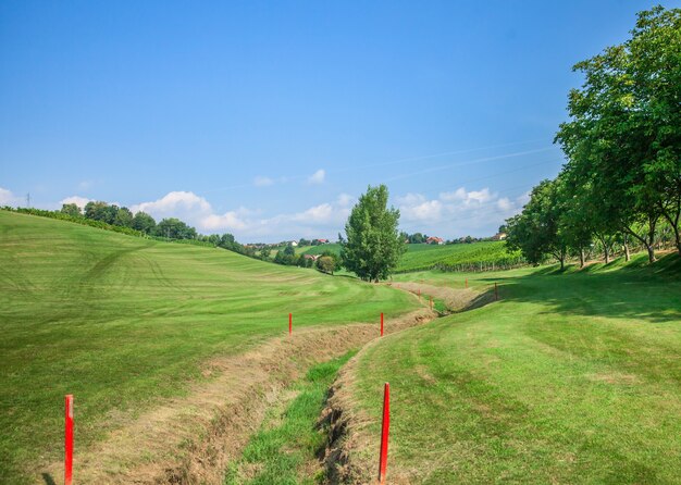 Trinchera en el campo de golf Zlati Gric marcado con marcadores rojos en un día soleado