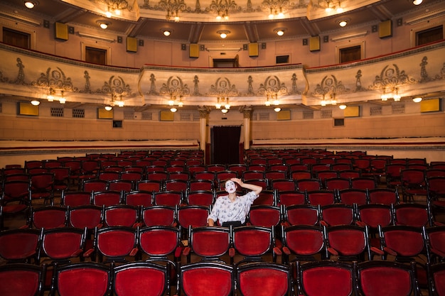 Triste artista femenino mime sentado solo en un auditorio