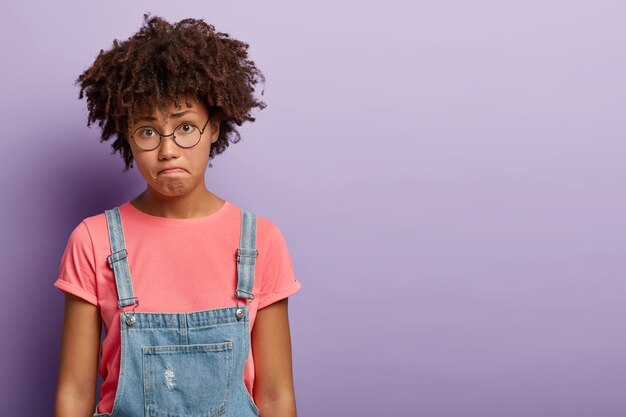 Triste desconcertado joven con un afro posando con un mono