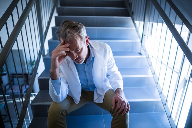 Triste doctor sentado en la escalera