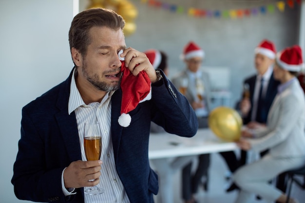 Triste hombre de negocios llorando mientras estaba en la fiesta de año nuevo en la oficina
