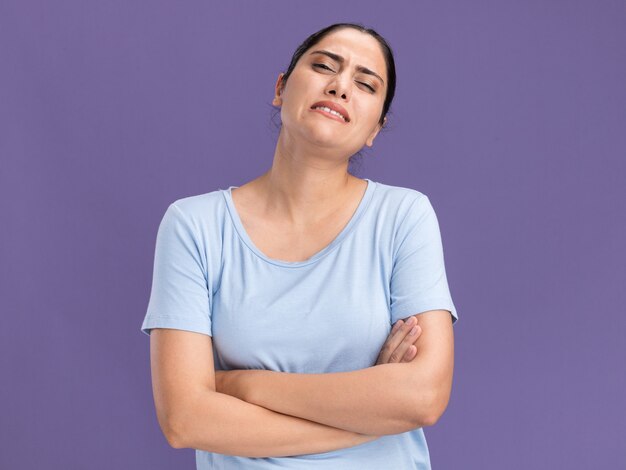 Triste joven morena caucásica de pie con los brazos cruzados.