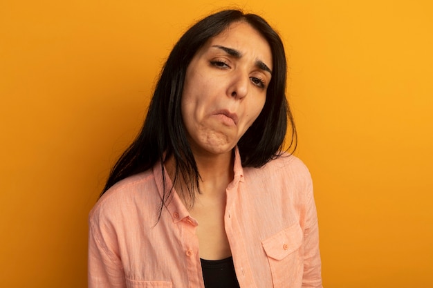 Triste mirando hacia adelante hermosa joven vestida con camiseta rosa aislada en amarillo