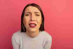 Foto gratuita triste mujer bonita mira al frente aislado en la pared rosa