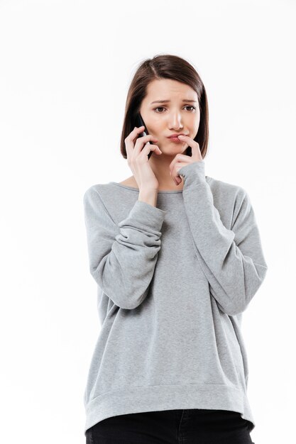 Triste mujer caucásica joven hablando por teléfono.