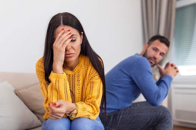 Triste niña pensativa pensando en problemas de relaciones sentada en un sofá con conflictos de novio ofendido en el matrimonio