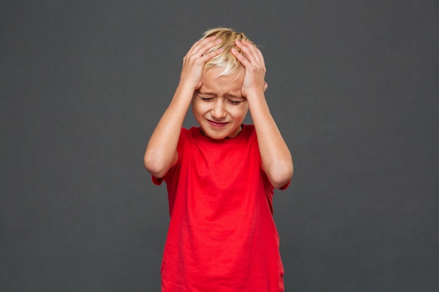 Triste niño pequeño con dolor de cabeza